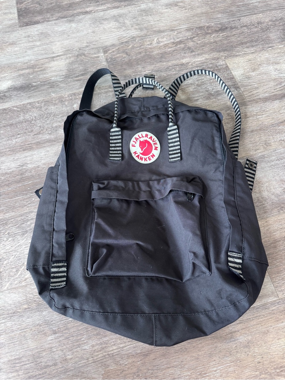 Black Backpack with black-and-white striped carry handles and shoulder straps